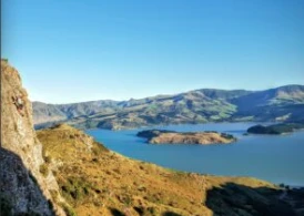 Lyttelton Harbour including Quail island and a person climbing on the rocks to the left