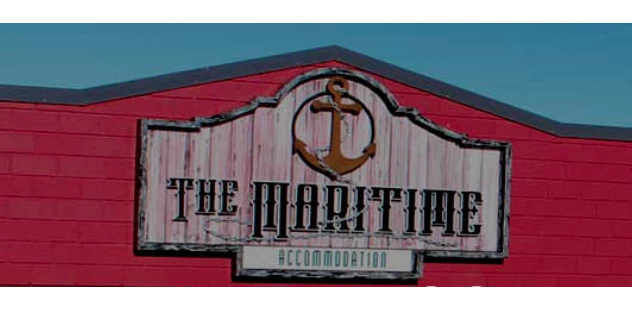 Image of the sign saying The Maritime with an anchor and rope logo at the top. pink background to the wooden sign