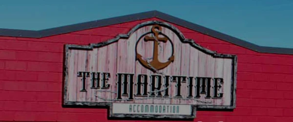 Image of the sign saying The Maritime with an anchor and rope logo at the top. pink background to the wooden sign