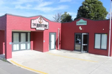 the front entrance of The Maritime painted red l shaped building with several windows and signage above the door.