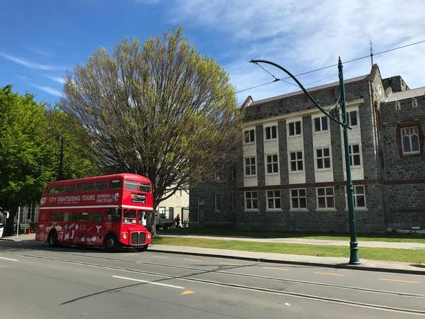 red double decker bus in from of a building in Christchurch new zealand