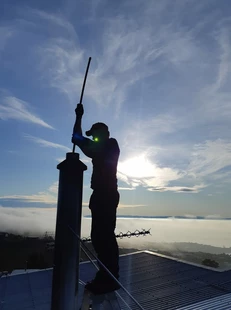 Image of man cleaning a chimeny with the Lyttelton harbour for harbour side fires