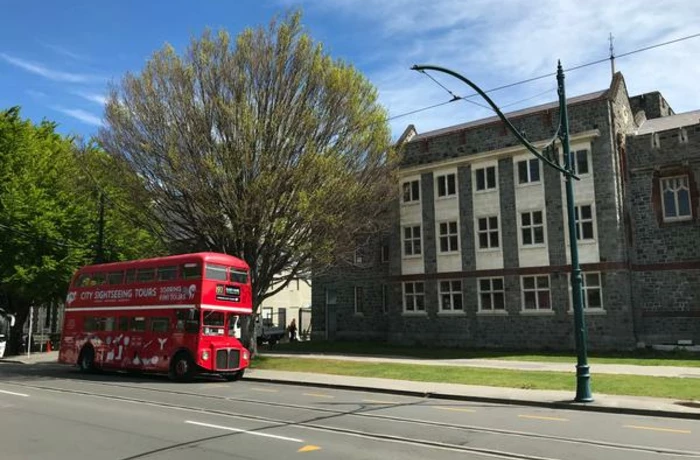 red double decker bus in from of a building in Christchurch new zealand