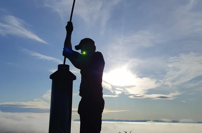 Image of man cleaning a chimeny with the Lyttelton harbour for harbour side fires